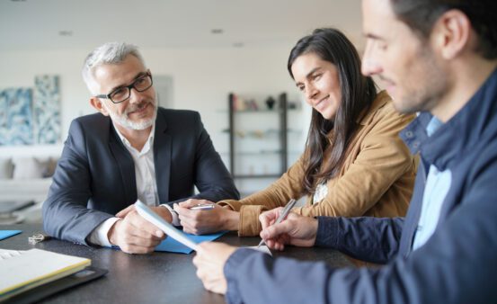 Happy couple meeting with business professional to review paperwork