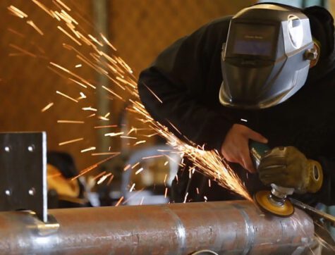 Missoula College construction students welding pieces of the Clearwater bus shelter.