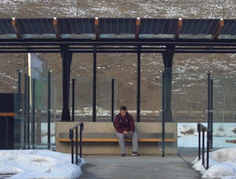 Missoula college student sitting in completed bus shelter waiting for a bus.