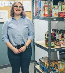 Employee at the UM Food Pantry showing off the recently stocked shelves.