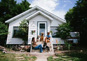 Two women and a dog sitting of the front steps to a white house in Missoula, MT