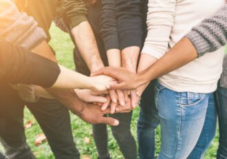 Multiracial Group of Friends with Hands in Stack demonstrating teamwork.