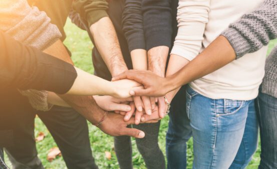 Multiracial Group of Friends with Hands in Stack demonstrating teamwork.