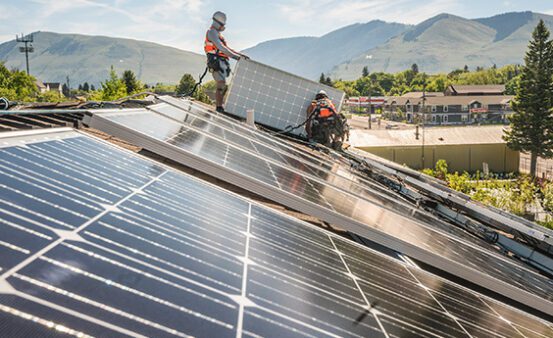 Two men installing solar panels on the Clearwater HQ building.