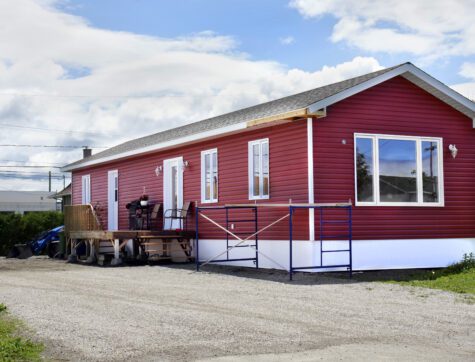 Newly constructed red vinyl siding mobile home at the local trailer park.