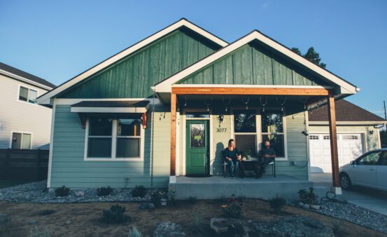 Man and woman sitting on their front porch with their dog at sunset.