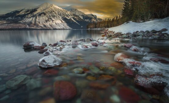 Early morning photo of the sun rising over the mountain at Lake McDonald in Glacier National Park in Montana.