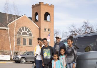 Clearwater Credit Union member, Desbele Tekle and his family in front of their car.