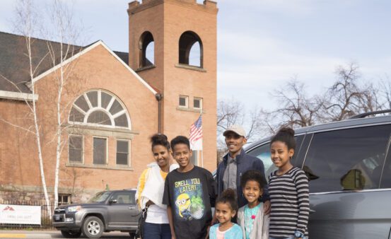 Clearwater Credit Union member, Desbele Tekle and his family in front of their car.