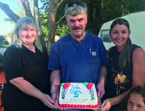 Two women and one man hold a cake to celebrate turning their mobile home park in to a Resident Owned Community (ROC).