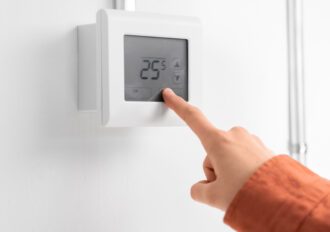 close up of hand setting room temperature on thermostat at home