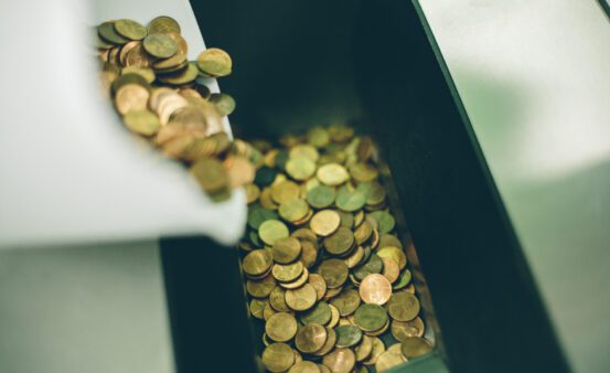 Close up of coins going in to a coin counter machine.