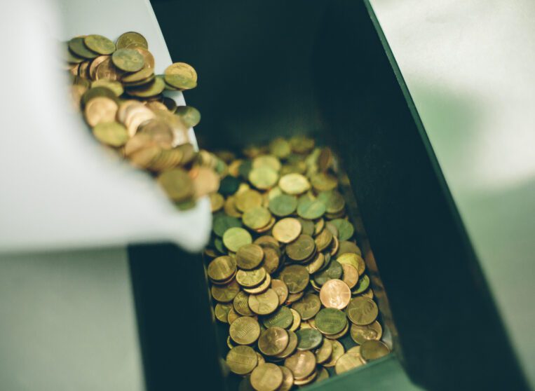 Close up of coins going in to a coin counter machine.