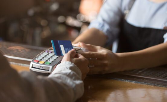 Contactless payment concept, female customer holding credit card near nfc technology on counter, client make transaction pay bill on terminal rfid cashier machine in restaurant store, close up view