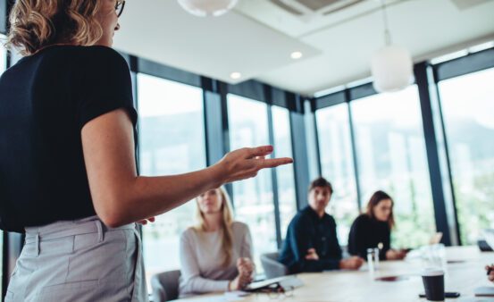 Businesswoman making a presentation to her colleagues in office. Office colleagues sitting at the conference room while listening to a presentation.