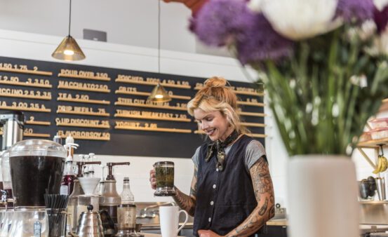 Young woman pouring coffee in local cafe.