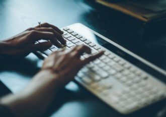 close up of womans hands typing on a computer keyboard.