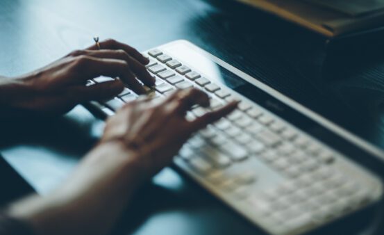 close up of womans hands typing on a computer keyboard.