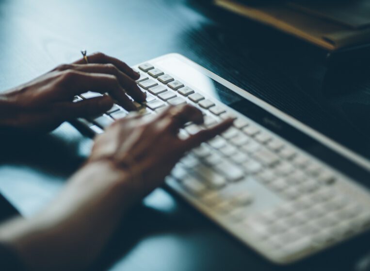 close up of womans hands typing on a computer keyboard.