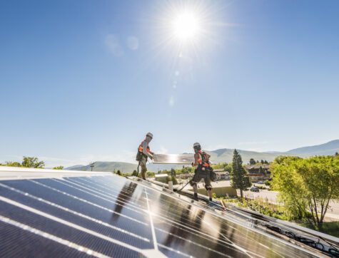 Two men installing solar panels on the Clearwater HQ building.