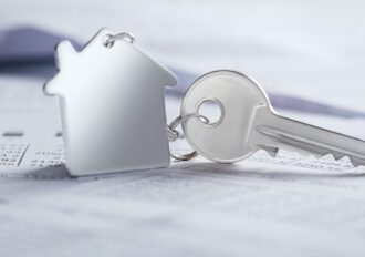 A home-shaped key ring is attached to a key sitting on top of paperwork.