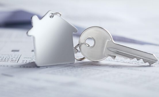 A home-shaped key ring is attached to a key sitting on top of paperwork.