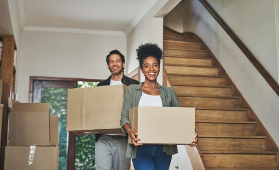 Happy young couple moving boxes in to their new home.