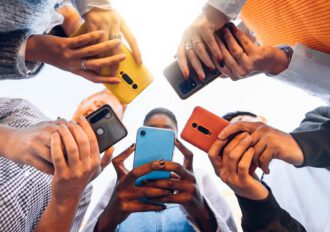 Teens in circle holding mobile phones.