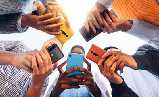 Teens in circle holding mobile phones.