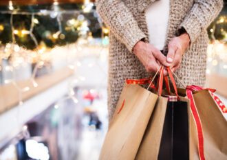 Unrecognizable senior woman with paper bags doing Christmas shopping. Shopping center at Christmas time.