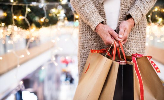 Unrecognizable senior woman with paper bags doing Christmas shopping. Shopping center at Christmas time.