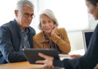 Modern senior couple reviewing items on tablet with a staff member.