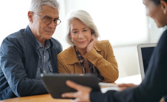 Modern senior couple reviewing items on tablet with a staff member.