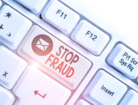 White pc keyboard with empty note paper above white background and one key that says "Stop Fraud."