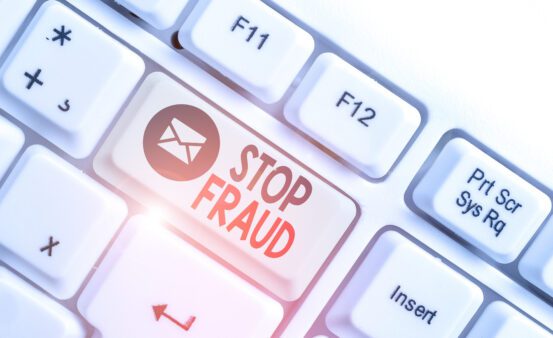 White pc keyboard with empty note paper above white background and one key that says "Stop Fraud."