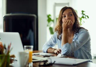 Young worried woman thinking of something while calculating her home budget.