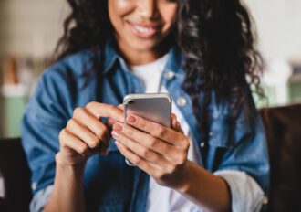 Cropped shot of a young woman using smart phone at home.