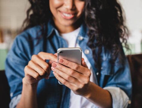 Cropped shot of a young woman using smart phone at home.