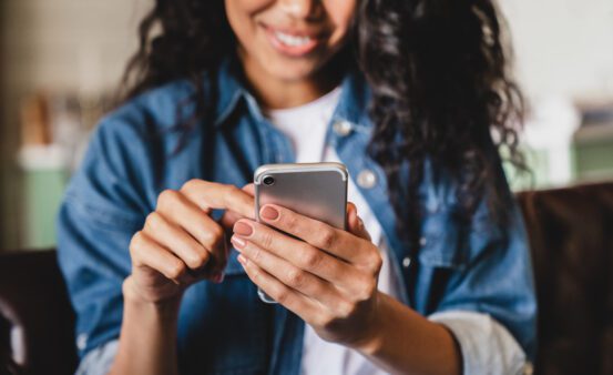 Cropped shot of a young woman using smart phone at home.