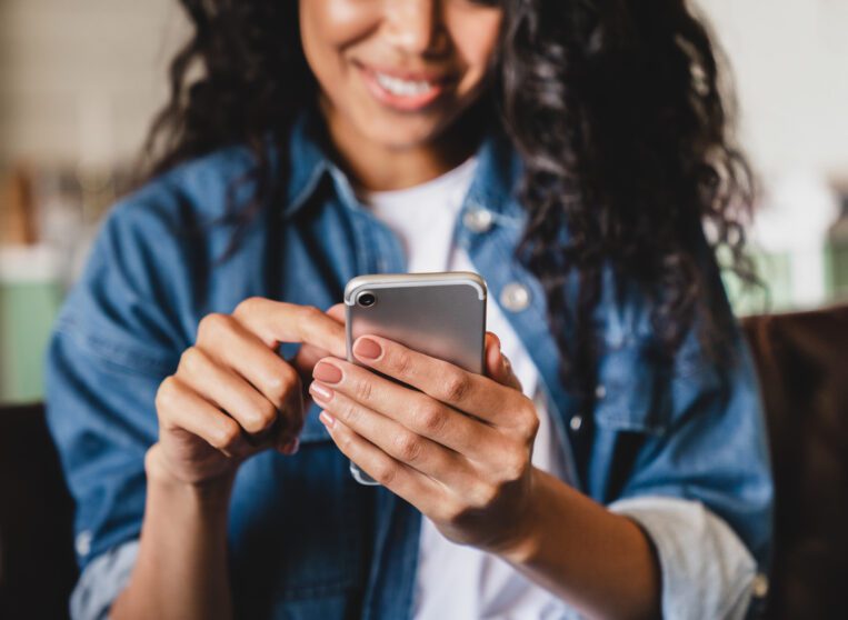 Cropped shot of a young woman using smart phone at home.