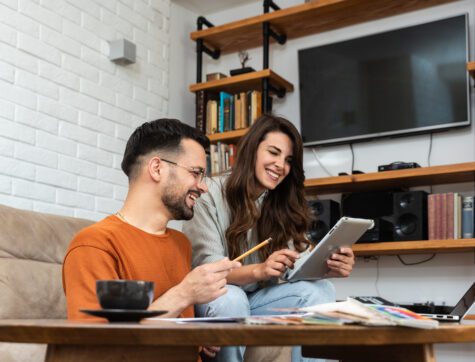 Young couple working from home on a tablet in their living room.