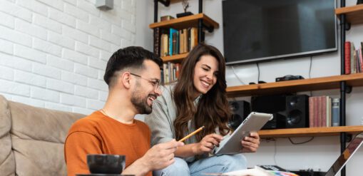 Young couple working from home on a tablet in their living room.