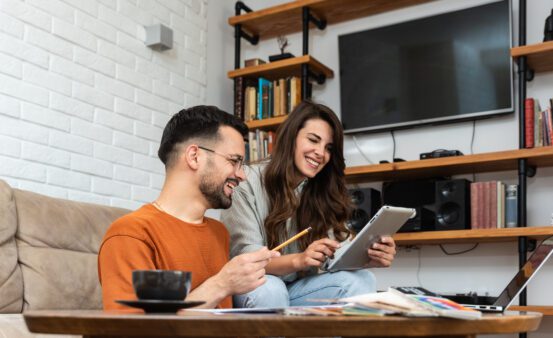 Young couple working from home on a tablet in their living room.