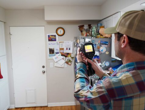 A man in a hat measuring house temperatures
