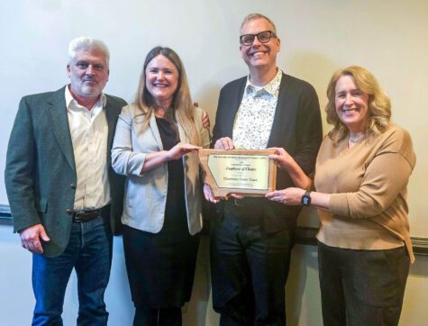 Four people smiling and holding an award