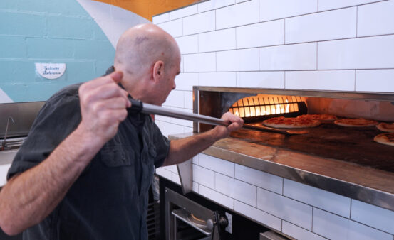 Man putting pizza in commercial oven